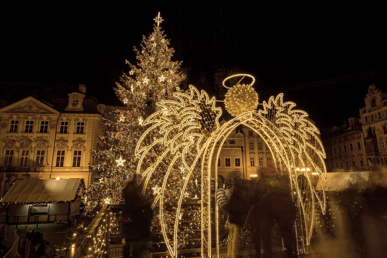 Rozsvícený vánoční strom a světelná brána s andělem na náměstí v noci