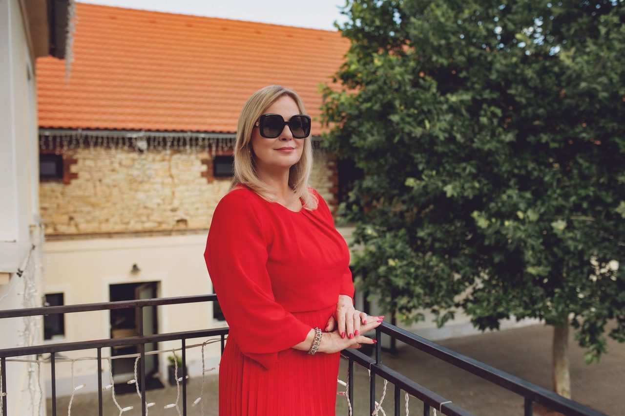 Eva Poláčková v červených šatech a slunečních brýlích na balkoně