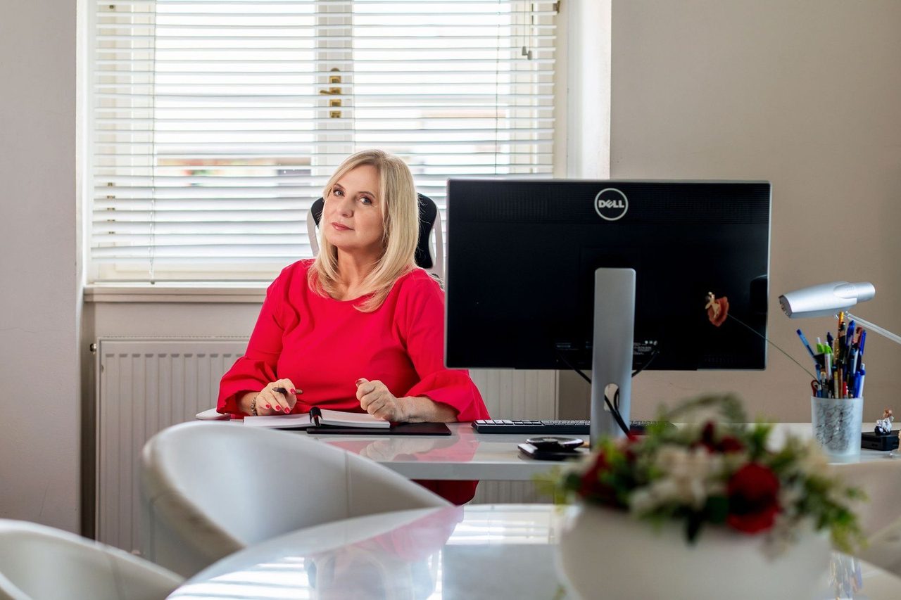 Eva Poláčková v červených šatech u pracovního stolu